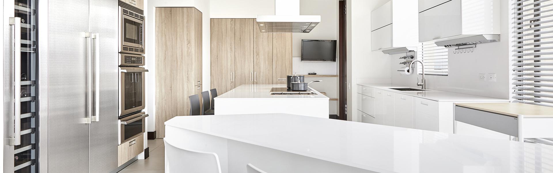 Cocina blanca con isla y abierta al salón equipada con muebles diseñados por Santos