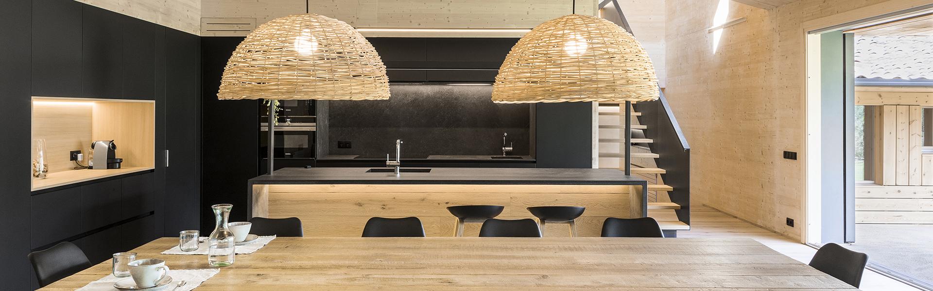 Cocina negra con isla y abierta al salón equipada con muebles diseñados por Santos